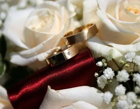 Immagine delle fedi su un bouquet di rose bianche.