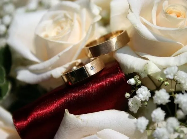Immagine delle fedi su un bouquet di rose bianche.