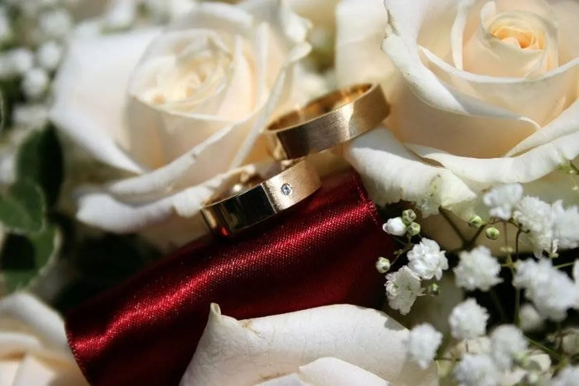 Immagine delle fedi su un bouquet di rose bianche.