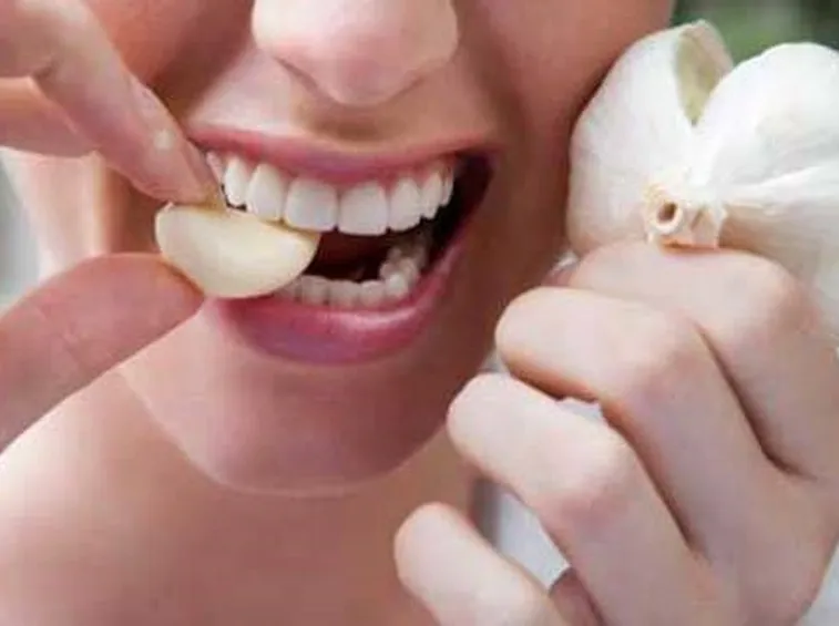 Foto di una ragazza che mangia l'aglio crudo