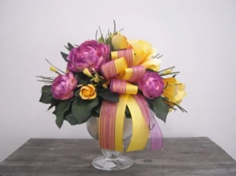 Composizione di vaso con fiori finti e nastrini colorati